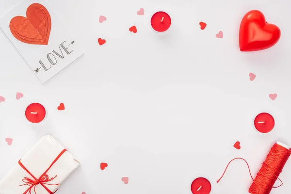 Top view of gift box, paper hearts and greeting card with 'love' lettering isolated on white with copy space, st valentines day concept — Stock Photo