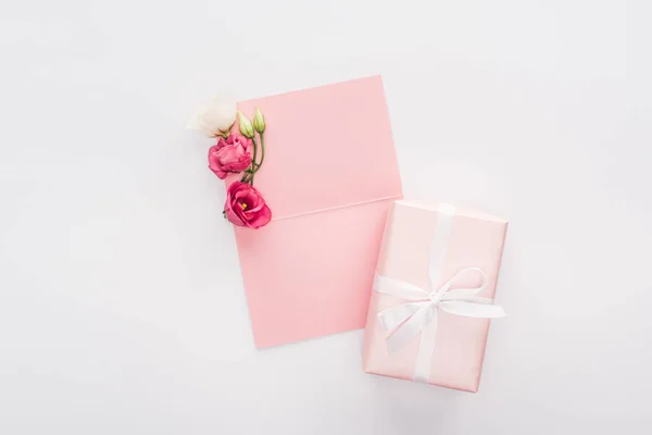 Vue du haut de la carte rose vierge, boîte cadeau et fleurs isolées sur blanc — Photo de stock