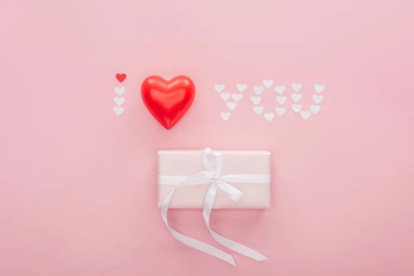 Top view of gift box and 'i love you' lettering made of paper hearts isolated on pink, st valentines day concept — стоковое фото