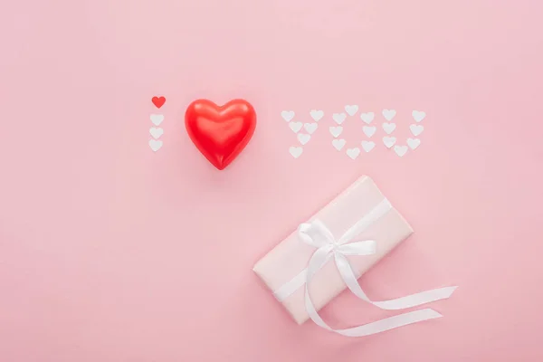 Vista superior de la caja de regalo y letras 'te amo' hechas de corazones de papel aislados en rosa, San Valentín concepto de día - foto de stock