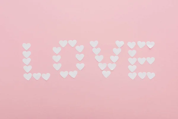 Top view of 'love' word made of paper hearts isolated on pink, st valentines day concept — Stock Photo