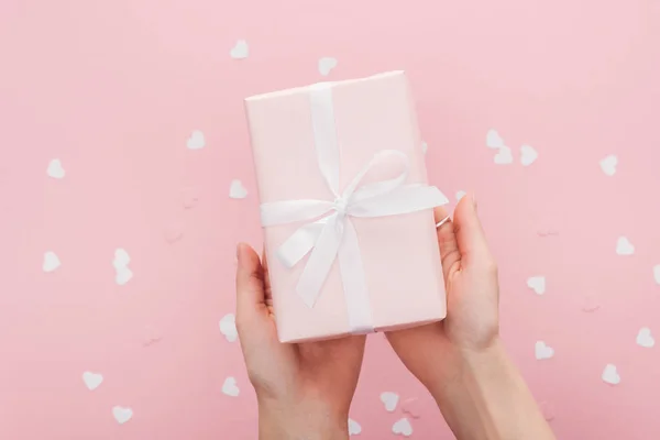 Vista cortada de mulher segurando caixa de presente e corações de papel isolados em rosa — Fotografia de Stock