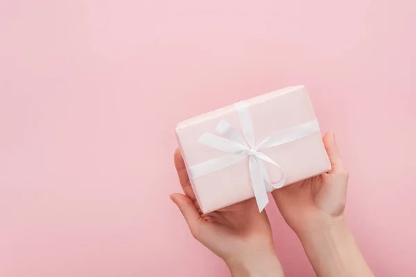 Vista recortada de la mujer sosteniendo caja de regalo aislado en rosa con espacio de copia - foto de stock