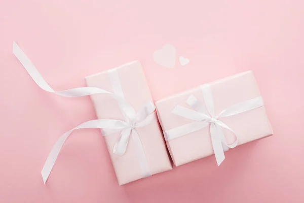 Top view of gift boxes with ribbons and paper hearts isolated on pink — Stock Photo