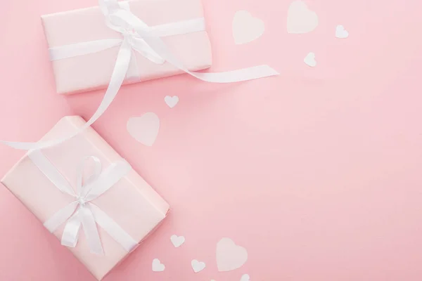 Top view of gift boxes with ribbons and paper hearts isolated on pink with copy space — Stock Photo
