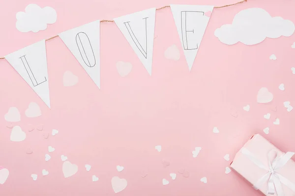 Top view of paper garland with 'love' lettering and gift box isolated on pink, st valentines day concept — Stock Photo