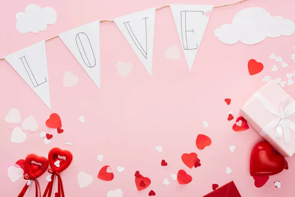 Top view of valentines decorations and paper garland with 'love' lettering isolated on pink with copy space, st valentines day concept — Stock Photo