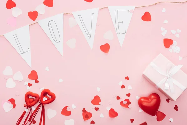 Top view of valentines decorations and paper garland with 'love' lettering isolated on pink, st valentines day concept — Stock Photo