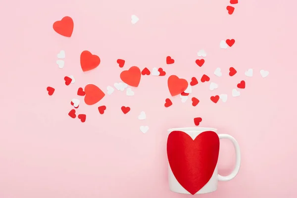 Верхний вид бумаги сердца и чашки с наклейкой в форме сердца изолированы на розовый, День святого Валентина концепции — стоковое фото