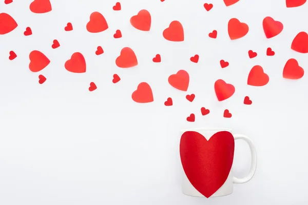 Top view of paper hearts and cup with heart shaped sticker isolated on white, st valentines day concept — Stock Photo