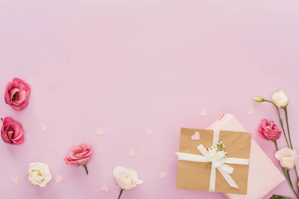 Vue du haut des coffrets cadeaux, fleurs et cœurs isolés sur rose avec espace de copie — Photo de stock