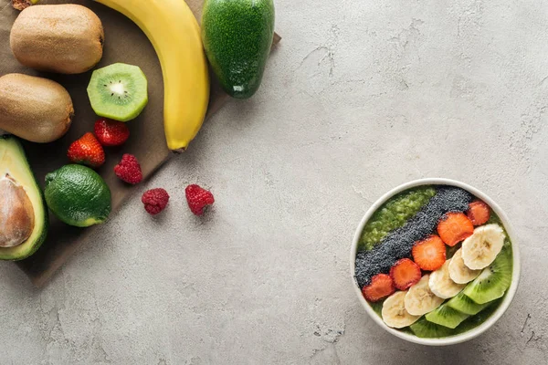 Vue du dessus du bol à smoothie avec des fruits et des ingrédients frais sur fond gris — Photo de stock