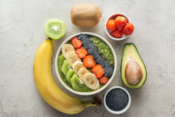 Top view of delicious smoothie bowl with fresh fruits on grey background — Stock Photo