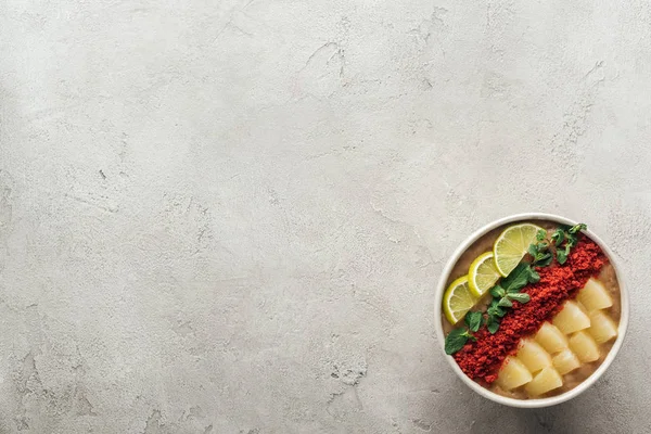 Vista superior de tigela de smoothie fresco com limões, hortelã e abacaxis em fundo cinza com espaço de cópia — Fotografia de Stock