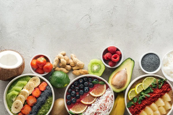 Vista superior de tigelas de smoothie saudáveis com ingredientes em fundo cinza — Fotografia de Stock