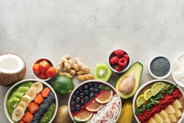 Top view of healthy smoothie bowls with ingredients on grey background — Stock Photo