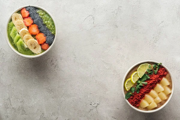 Vista superior de tigelas de smoothie orgânicos saudáveis com frutas em fundo cinza com espaço de cópia — Fotografia de Stock