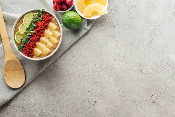 Верхний вид вкусной миски смузи с ингредиентами на сером фоне с копировальным пространством — стоковое фото