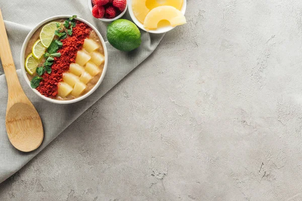 Vue du dessus du délicieux bol à smoothie avec des ingrédients sur fond gris avec espace de copie — Photo de stock