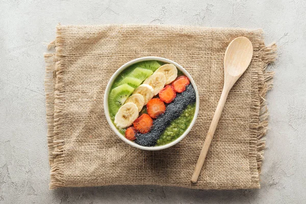 Vue du dessus du bol à smoothie frais sur sac avec cuillère en bois — Photo de stock