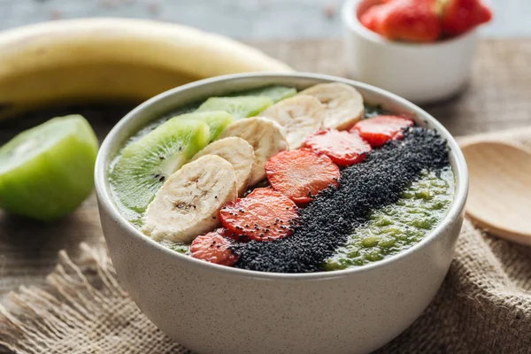 Selective focus of smoothie bowl with bananas, strawberries and poppy seeds on sackcloth — Stock Photo