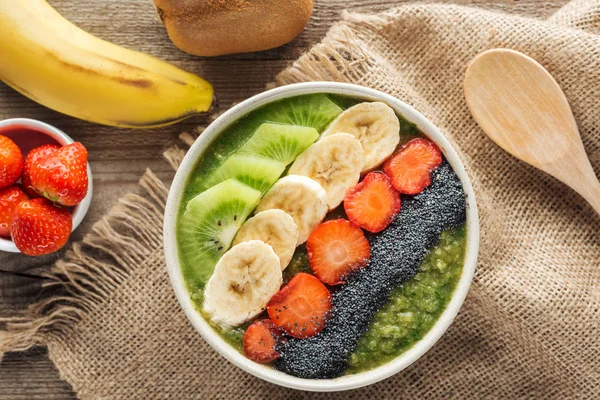 Top view of fresh smoothie bowl with ingredients on sackcloth — Stock Photo