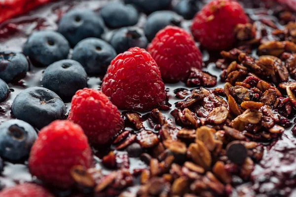 Selective focus of blueberries, raspberries and granola in smoothie bowl — Stock Photo
