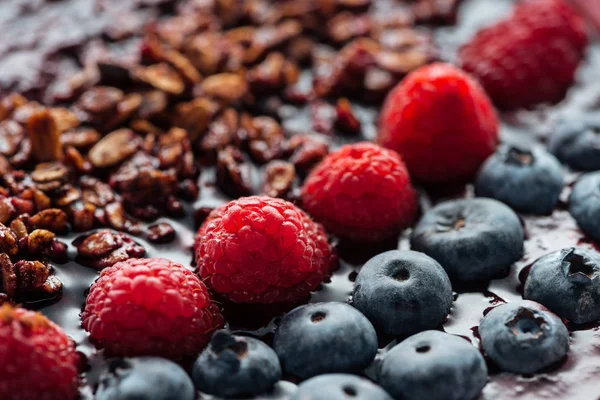 Selective focus of blueberries, raspberries and granola in smoothie bowl — Stock Photo