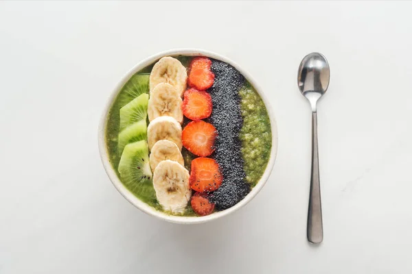 Top view of smoothie bowl with fresh fruits and spoon on white background — Stock Photo