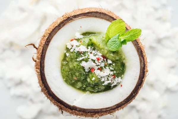 Vue de dessus du smoothie vert frais en noix de coco décoré avec de la menthe — Photo de stock