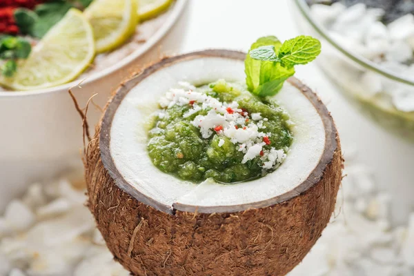 Селективний фокус свіжої зеленої смузі в кокосовому горіху, прикрашеному м'ятою — стокове фото