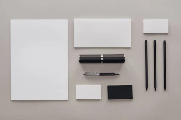 Pose plate avec papiers blancs vierges, cartes et papeterie sur fond gris — Photo de stock