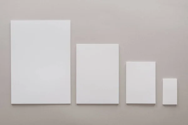 Vista superior de papéis brancos em branco com espaço de cópia em fundo cinza — Fotografia de Stock