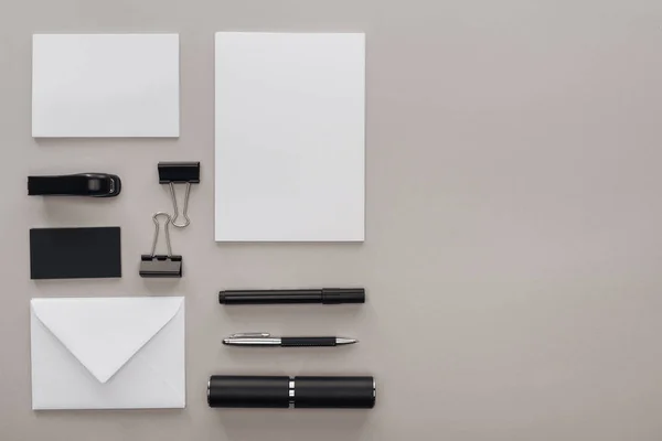 Pose plate avec papeterie noire et blanche sur le lieu de travail sur fond gris avec espace de copie — Photo de stock