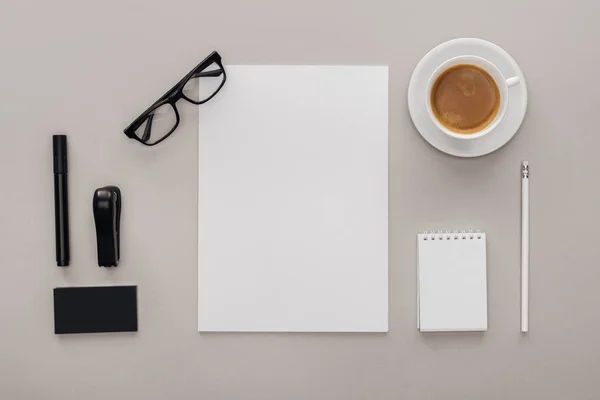 Ansicht von Schwarz-Weiß-Schreibwaren am Arbeitsplatz mit Tasse Kaffee auf grauem Hintergrund — Stockfoto