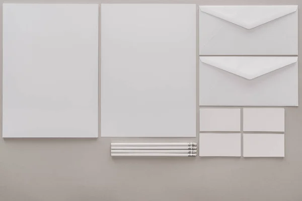 Flat lay com papéis brancos vazios e envelopes sobre fundo cinza — Fotografia de Stock