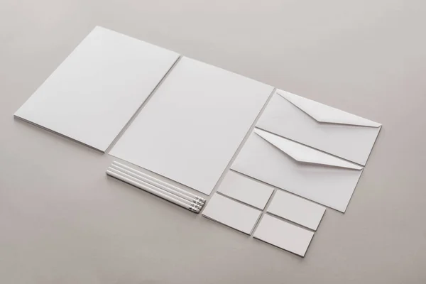 Flat lay with white empty papers, cards, envelopes and pencils on grey background — Stock Photo