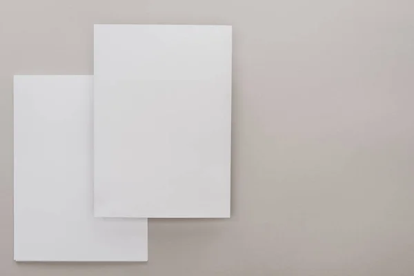 Vista superior de los papeles blancos vacíos sobre fondo gris - foto de stock