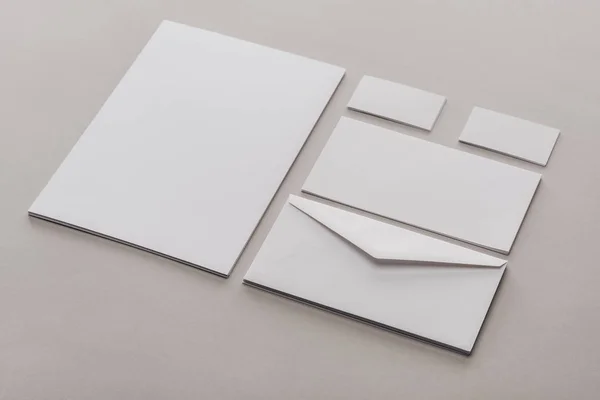 Flat lay with white empty papers and envelopes on grey background — Stock Photo