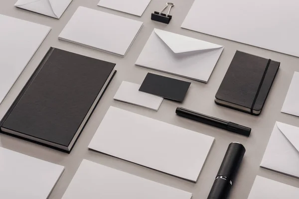 Posa piatta con carte bianche vuote e forniture per ufficio nere su sfondo grigio — Foto stock