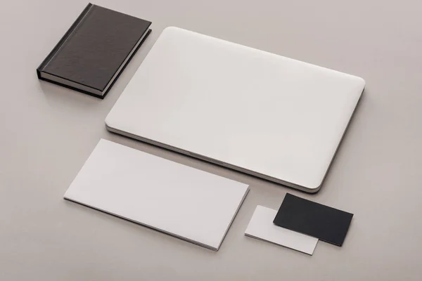 Flat lay with black and white empty cards and laptop on grey background — Stock Photo