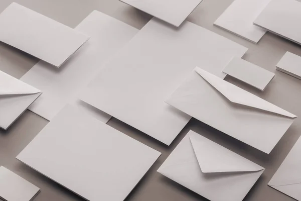 Close up of empty white papers and envelopes on grey background — Stock Photo