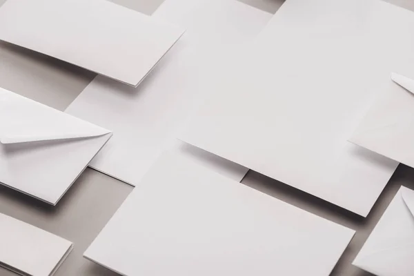 Flat lay with white papers and envelopes on grey background — Stock Photo