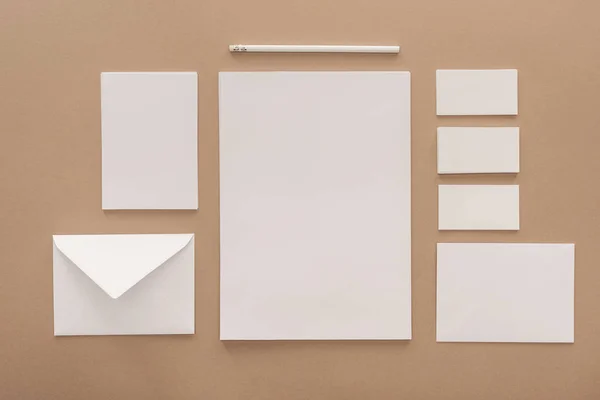 Envelope, pencil, cards and sheets of paper on beige background — Stock Photo