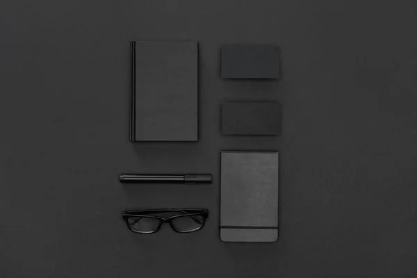 Brille, Notizbuch, Karten und Stift auf schwarzem Hintergrund — Stockfoto