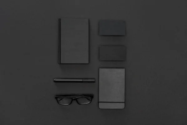 Glasses, notebook, cards and pen on black background — Stock Photo