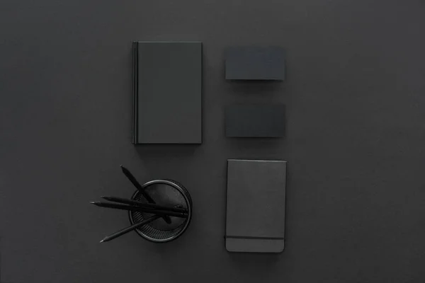 Вид сверху на ручки, тетради и открытки на черном фоне — стоковое фото