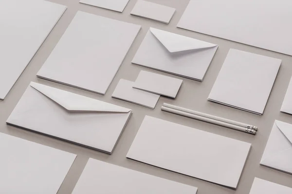 Acostado plano con lápices blancos, sobres, tarjetas vacías y hojas de papel - foto de stock