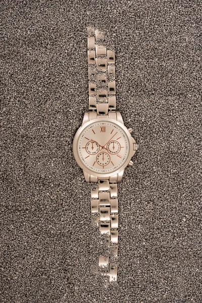 Vista superior del reloj de pulsera dorado tumbado en la arena - foto de stock
