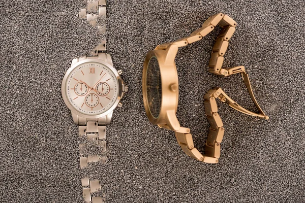 Top view of wristwatches lying on golden sand — Stock Photo